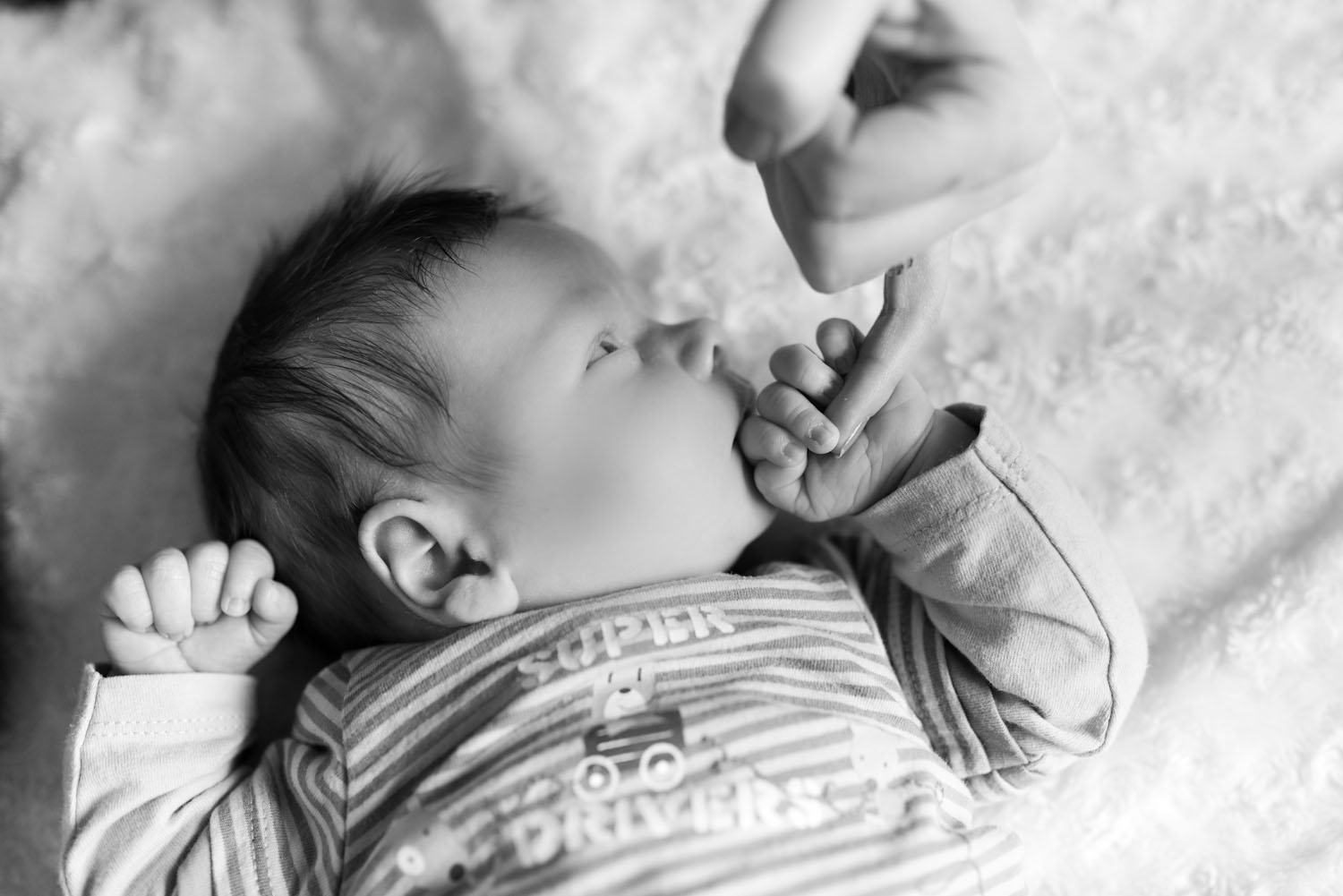 Bébé en noir et blanc qui tiens la main de sa mère